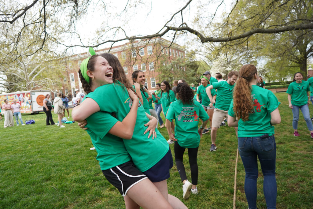 Two students both wearing green, are hugging on Jefferson Square.